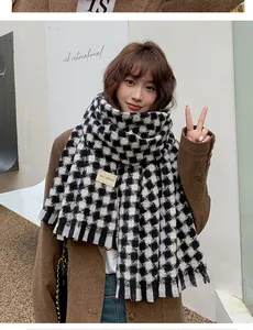 Close-up of thick black and white houndstooth scarf with soft fringe and textile label