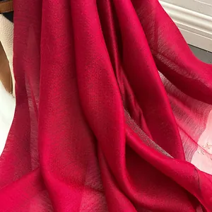 Gros plan de la texture du foulard en soie rouge avec broderie fine et éclat nacré