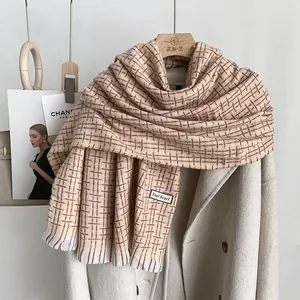 Dettaglio di sciarpa invernale a quadri con frange ed etichetta Feel Scarf