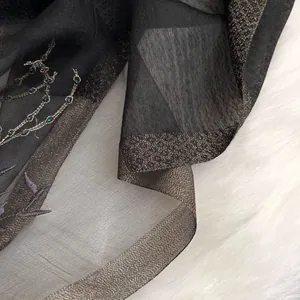 Detail of embroidered silk wool scarf with champagne gold trim and beaded accents