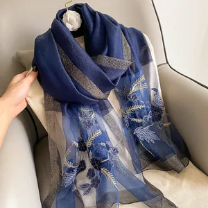Detailed close-up of navy silk wool scarf featuring golden stripes and floral embroidery