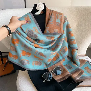 Detail of blue and orange scarf featuring cartoon cat patterns and fine fringe edges
