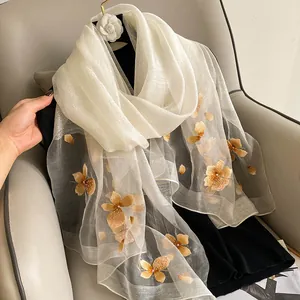 Detailed embroidery on cream silk wool scarf featuring golden floral patterns