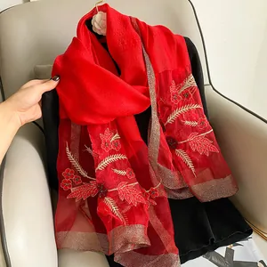 Close-up of red silk scarf with intricate floral embroidery and gold thread edging