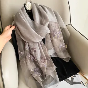 Détail d'un châle en soie et laine brodé avec fleurs 3D lavande et broche camélia