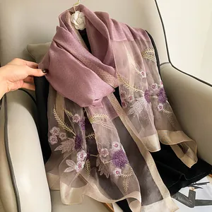Detailed embroidery on a lilac silk-wool scarf with gold metallic trim and floral patterns
