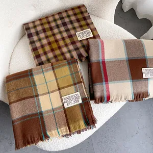 Detail view of premium plaid wool scarves with fringed edges and brand labels on sheepskin