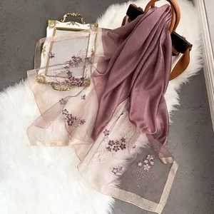 Détail de la broderie florale sur une écharpe en soie violette avec bordure en tulle