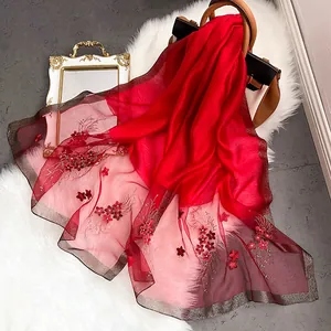 Détail d'une écharpe en soie rouge foncé avec broderies et bords en fil d'argent