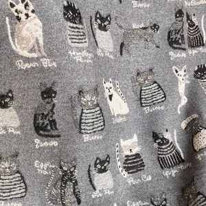 Detail of woven kitten patterns and text on grey cashmere-like scarf fabric texture