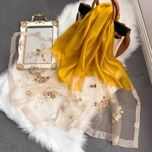 Détail d'une écharpe en soie avec broderie florale et organza sur tapis en fausse fourrure