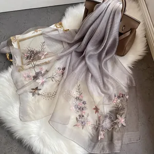 Elegant grey silk wool scarf with intricate floral embroidery on a soft plush background