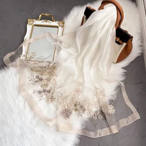 Detail view of exquisite floral embroidery and pearls on a sheer silk wool shawl
