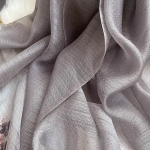 Macro detail of silver-grey silk wool scarf showing delicate pleated texture and subtle sheen