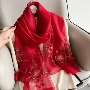 Detail view of red silk wool scarf featuring golden floral embroidery and organza stitching