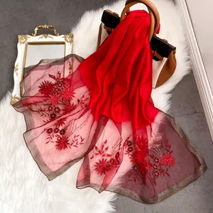 Detail of red silk wool shawl featuring floral embroidery and golden metallic edges