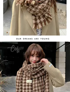 Detail of coffee houndstooth scarf with tassels and Self Service label on camel coat