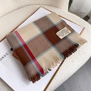 Close-up of retro plaid scarf with soft fringe edges and a minimalist brand woven label