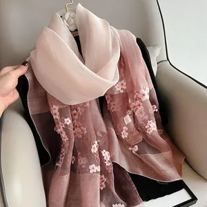 Close-up of pink gradient silk wool scarf with intricate cherry blossom embroidery details