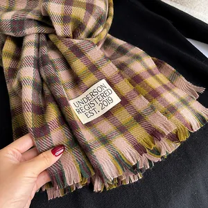 Detail of soft cashmere feel plaid scarf with fringe edge and brand tag