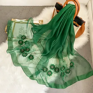 Gros plan détaillé d'une écharpe en soie vert foncé avec broderie florale et sequins fins