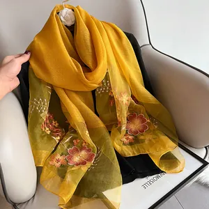 Detail of floral embroidery on lightweight golden silk wool scarf with intricate patterns