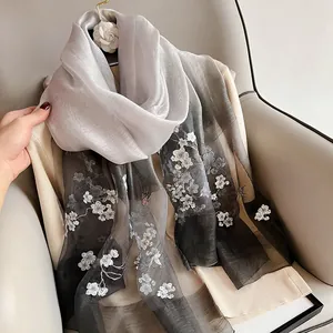 Detail of floral butterfly embroidery on gray gradient silk wool shawl with sheer texture