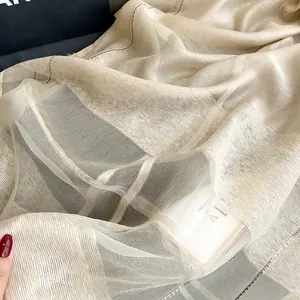 Detailed macro view of high-quality champagne silk scarf with fine texture and black stitching