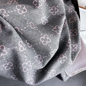 Detail of soft grey cashmere scarf with pink clover pattern and elegant fringe edges