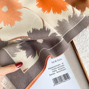 Gros plan d'un châle doux à fleurs orange avec des détails de franges élégantes