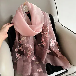 Detailed close-up of pink cherry blossom and butterfly embroidery on gradient silk scarf