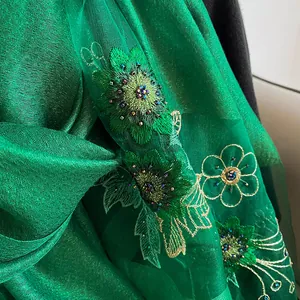 Détail de broderie et perles sur un luxueux châle en soie et laine vert foncé