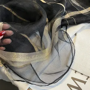 Gros plan détaillé du foulard en soie noir avec rayures métalliques dorées et argentées fines