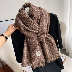 Detail of thick cashmere-like scarf showing brown houndstooth pattern and fringe edges