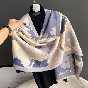 Détail d'une écharpe fleurie épaisse aux tons bleu gris et franges pour l'automne-hiver