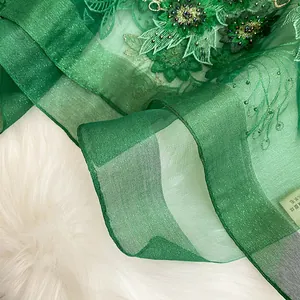 Macro d'une écharpe en soie et laine verte avec broderie lourde et travail de perles
