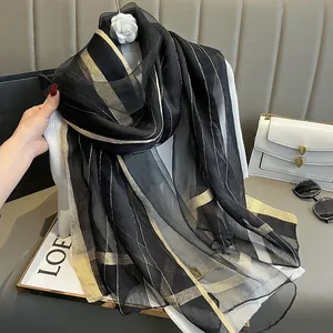 Détail d'une écharpe en soie noire avec des rayures dorées élégantes et texture légère