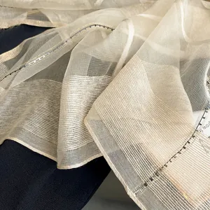 Macro shot of sheer beige silk mohair fabric with metallic threads and textured pattern