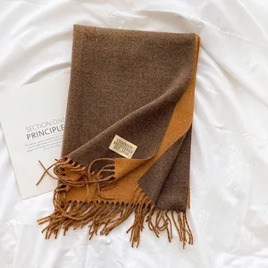 Detailed view of two-tone brown cashmere-like scarf with tassels and brand label