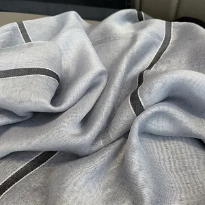 Vue détaillée de la texture du foulard en soie argentée et des bords rayés noir et blanc