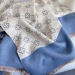 Detail of cashmere-like scarf showing beige clover pattern and gray tassels