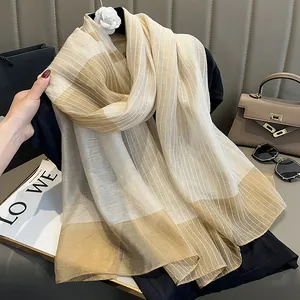 Gros plan d'une écharpe en soie et laine avec d'élégantes rayures beige et champagne
