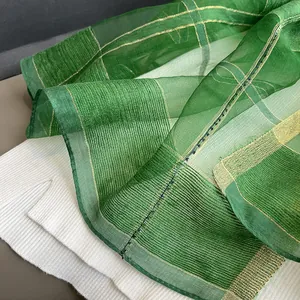Detailed macro view of green silk mohair scarf fabric with golden metallic thread