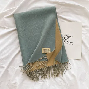 Detail of double-sided cashmere-like scarf showing blue and yellow fabric with fringe