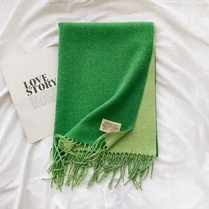 Detail of green cashmere-feel scarf showing soft texture, fringe edges and woven brand label