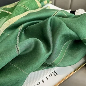 Detail of dark green silk mohair scarf featuring shimmering gold metallic thread stripes