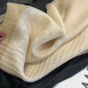 Gros plan détaillé de l'écharpe en soie beige montrant sa texture légère et ses rayures fines