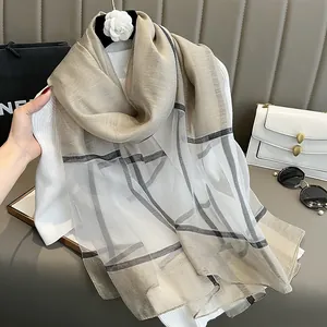 Détail d'un foulard en soie à carreaux avec bords roulés sur un pull en maille blanc
