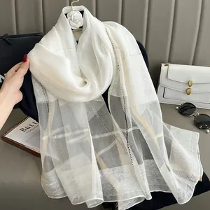 Detailed view of white silk mohair scarf with golden thread and woven grid texture