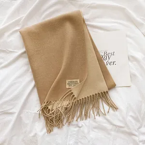 Close-up of camel cashmere scarf with decorative tassels and vintage woven brand label